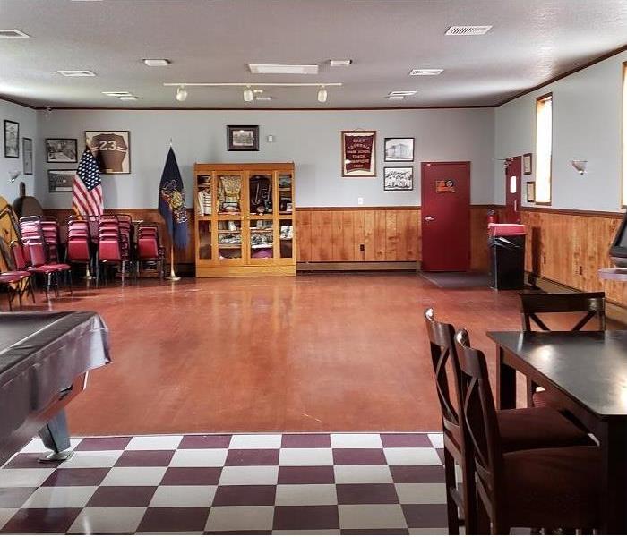 multiputpose room used for public events. Flags and stacked chairs in background; table and pool table in foreground